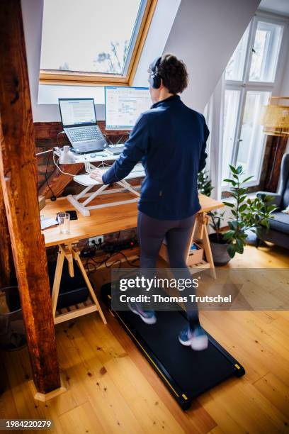 In this photo illustration a woman walks on a walking pad at her desk while working from home on February 07, 2024 in Berlin, Germany.