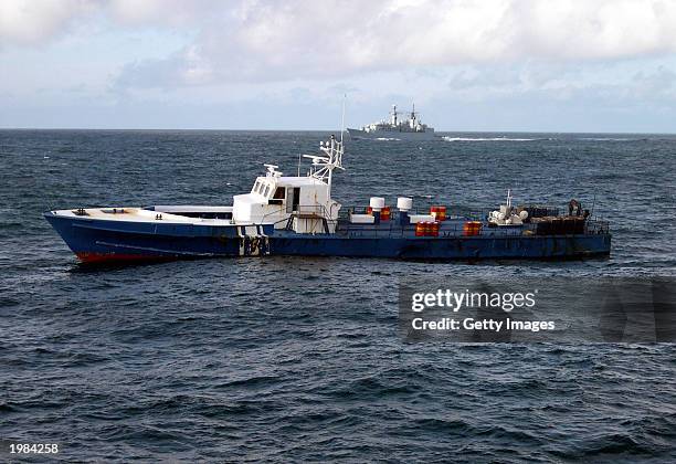 Royal Navy frigate HMS Cumberland stands guard over a converted motor torpedo boat, seized by British and Spanish Customs officers May 8, 2003 with a...