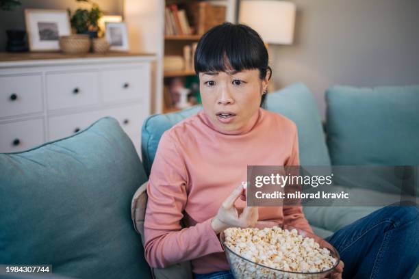 portrait of japanese woman eating popcorn - woman watching horror movie stock pictures, royalty-free photos & images