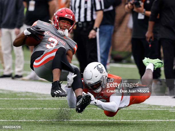 Wide Receiver Jamari Thrash of Louisville from the American Team is tackled by Cornerback Chau Smith-Wade of Washington State from the National Team...