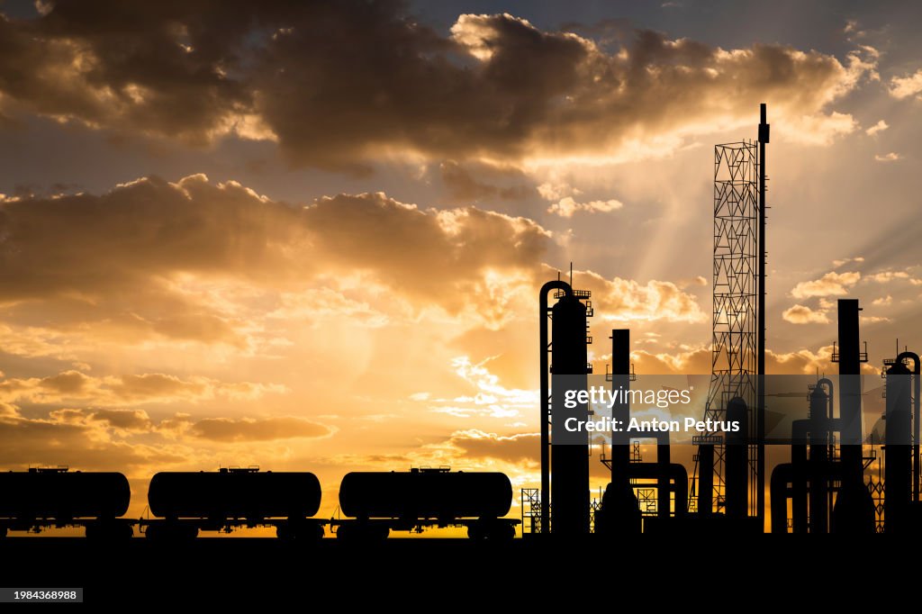 Oil refinery plant and fuel railway tank at sunset