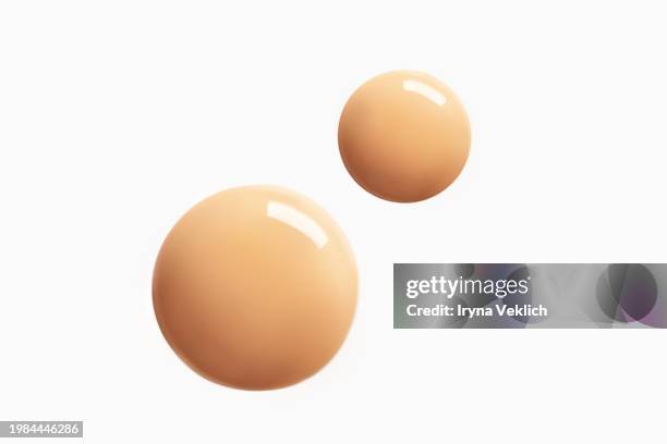 two round shape drops of thick make-up face foundation falling from pipette on white background. - fondotinta foto e immagini stock