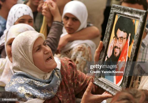 Lebanese woman holds a portrait of Sheikh Nasrallah, the leader of Hezbollah, during a rally, celebrating the departure of Israeli troops from...