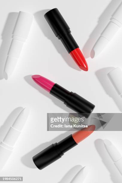 pink, red, beige lipsticks, lip gloss on beautiful creative white background. cosmetic products. makeup accessories. skin care. beauty 3d pattern, vertical composition. - red lipstick swatch stock pictures, royalty-free photos & images