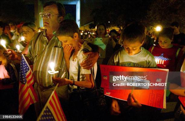 Jean Larsson weeps as she is comforted by her husband Roy Larsson as they and others attend a candlelight vigil at a local park in Brooklyn, New...