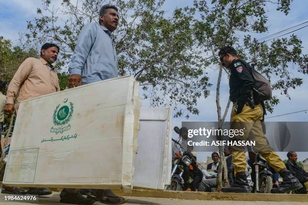 Election presiding officers walk past a policeman as they leave after collecting voting materials at a distribution center in Karachi on February 7 a...