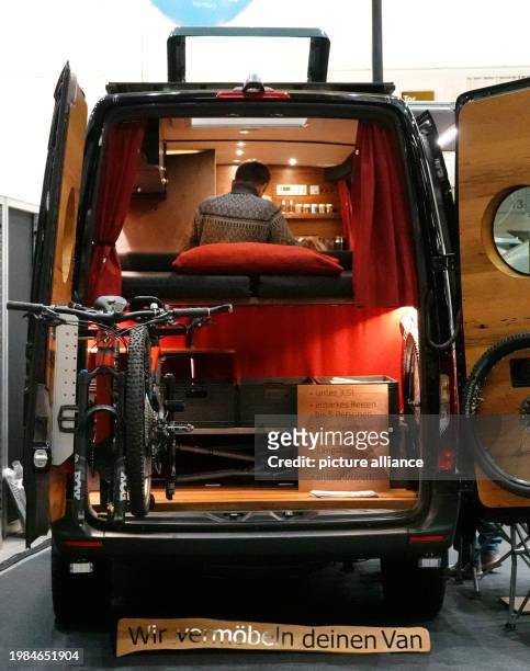 February 2024, Hamburg: A visitor takes a look inside a camper on the first day of the "Reisen und Caravaning" trade fair. The tourism trade fair...