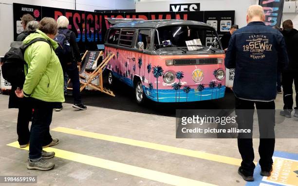 February 2024, Hamburg: Visitors look at a colorfully wrapped motorhome on the first day of the "Reisen und Caravaning" trade fair. The tourism trade...