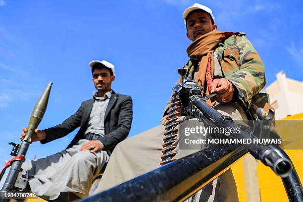 Armed supporters of Yemen's Huthi movement pose while carrying a machine gun and a rocket-propelled grenade launcher during a pro-Palestinian rally...