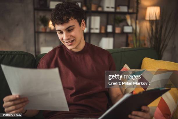 a teenager is sitting on a bed while concentrating on homework for exams. - day in the life series stock pictures, royalty-free photos & images