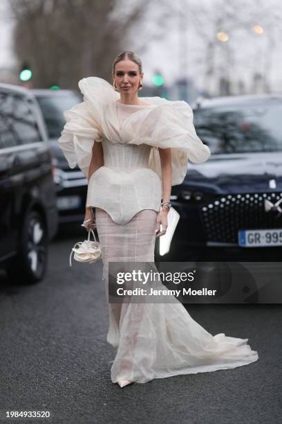 Leonie Hanne is seen wearing a voluminous white floor-length dress with transparent fabric and white details, a white corset top with ruffles, a...