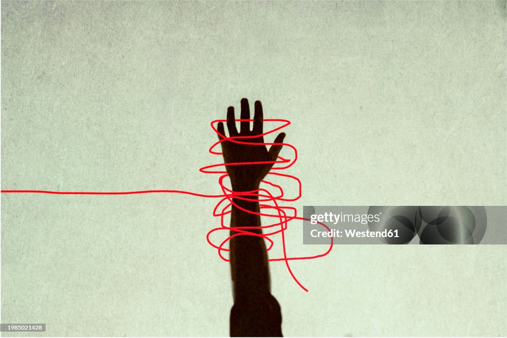 Human hand trapped in red tangled strings