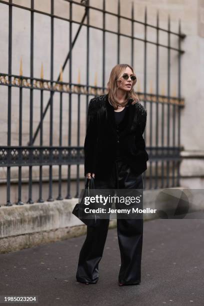 Viky Rader is seen wearing a black blazer with silver rhinestones on the shoulders, a black top underneath, wide black leather pants, a black leather...