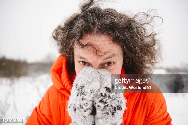 mature woman covering face with hands in mittens - woman hands in mittens stock-fotos und bilder