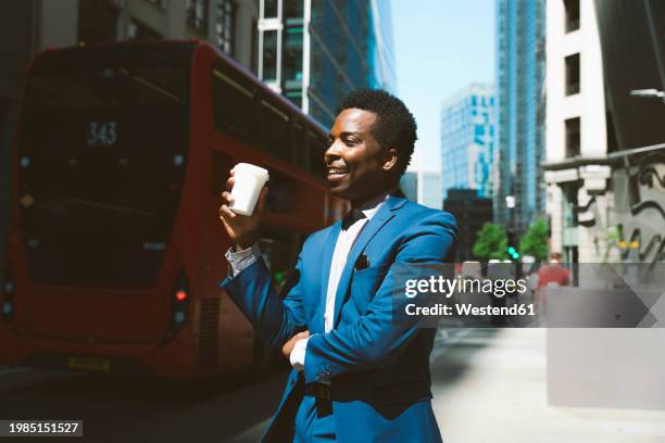 smiling businessman standing with coffee cup on sunny day - coffee to go cups stock pictures, royalty-free photos & images