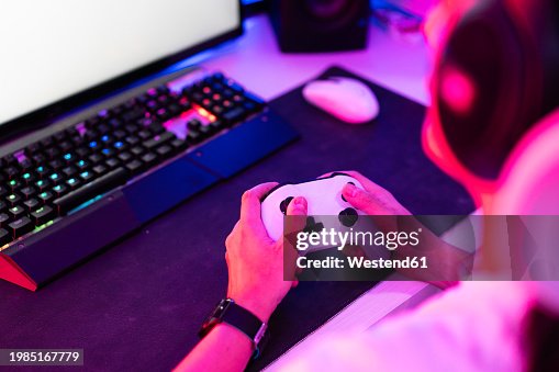Gamer holding gamepad and playing video game on desktop Gamer holding gamepad and playing video game on desktop