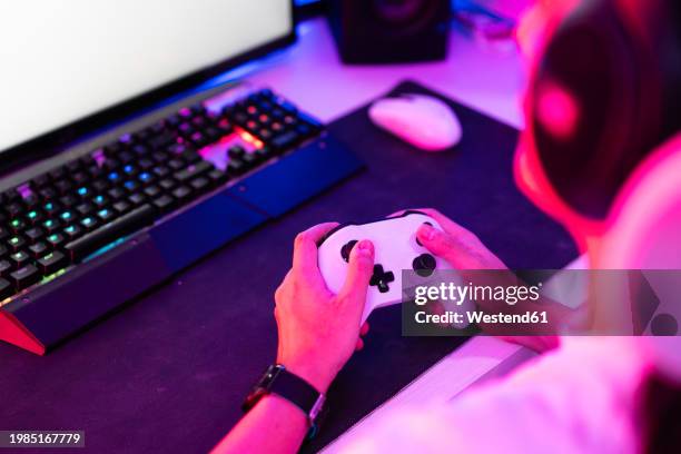 gamer holding gamepad and playing video game on desktop - videojuego fotografías e imágenes de stock