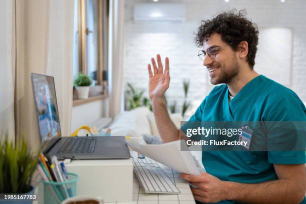 enfermero en bata, saludando a un paciente durante una videollamada - telemedicina fotografías e imágenes de stock