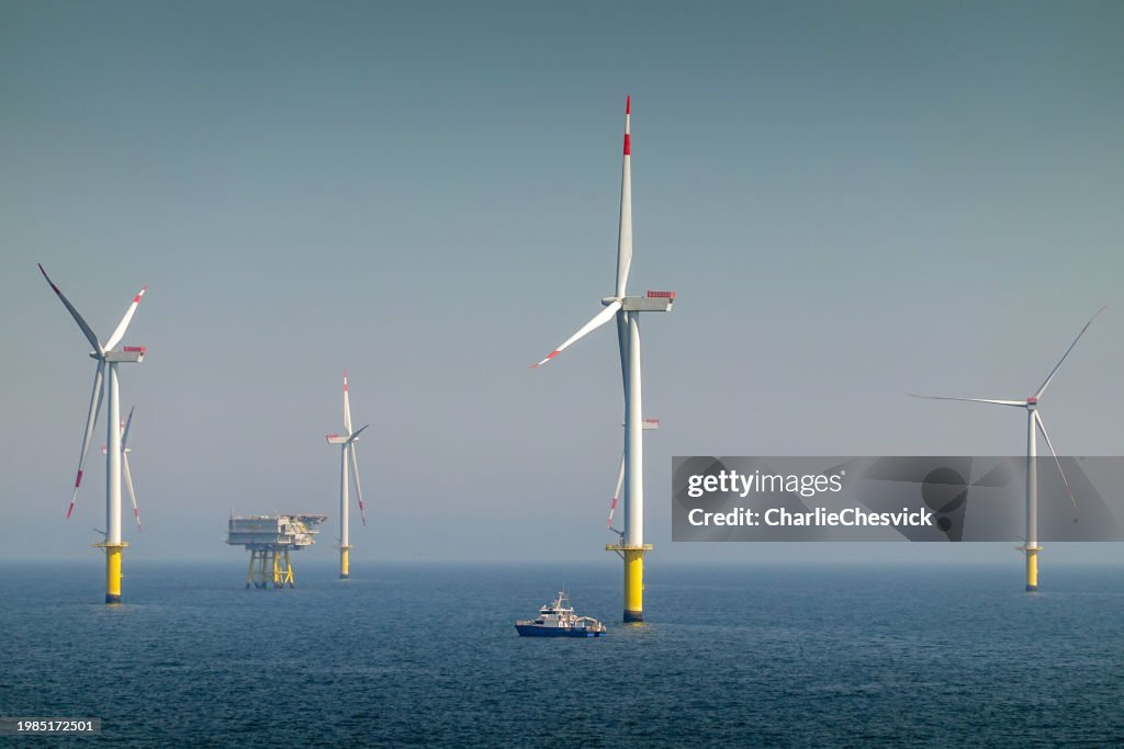 Epic Sunrise over Offshore Wind farm and substation on the horizont, vessel between them, bright sky, Borkum Riffgrund Germany