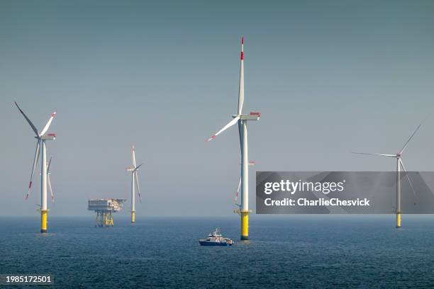 epic sunrise over offshore wind farm and substation on the horizont, vessel between them, bright sky, borkum riffgrund germany - north sea wind farm stock pictures, royalty-free photos & images