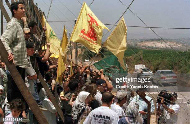 Lebanese demonstrators holding Hezbollah flags participate in a protest at the Lebanon-Israeli border fence, following the Israel's withdrawal from...