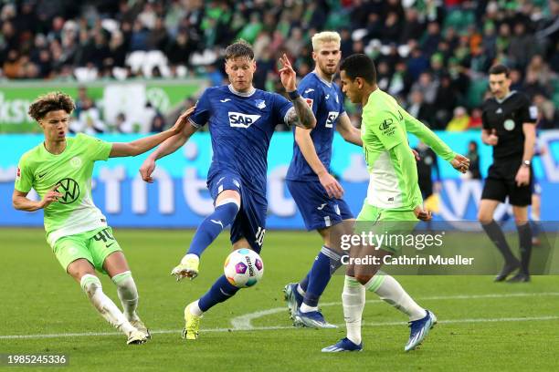Wout Weghorst of TSG 1899 Hoffenheim controls the ball whilst under pressure from Kevin Paredes and Rogerio of VfL Wolfsburg during the Bundesliga...
