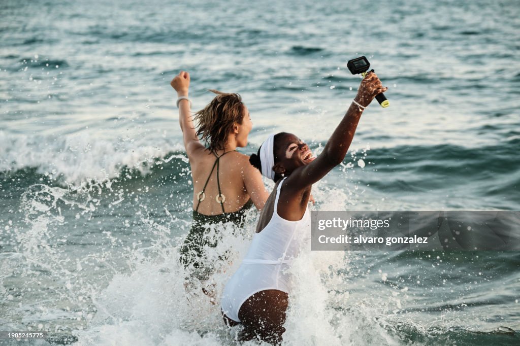 Two friends inside the water using a waterproof action camera
