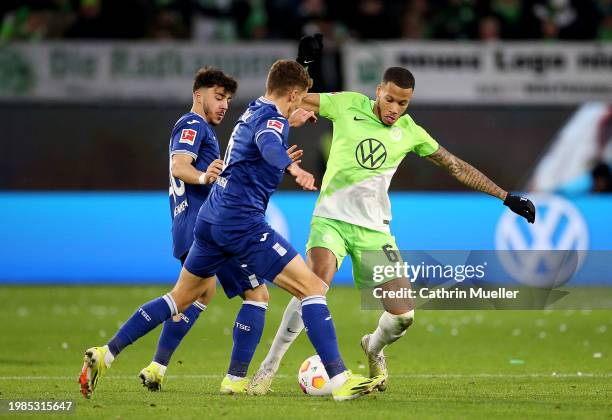 Aster Vranckx of VfL Wolfsburg battles for possession with Umut Tohumcu and Grischa Proemel of TSG 1899 Hoffenheim during the Bundesliga match...