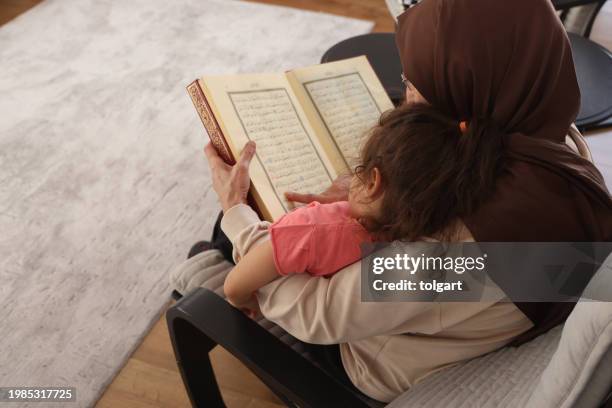 grandmother teaches her granddaughter to read the quran - koran stock pictures, royalty-free photos & images