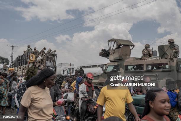 People gather next to some vehicles from the South African National Defence Force as part of the Southern African Development Community Mission as...
