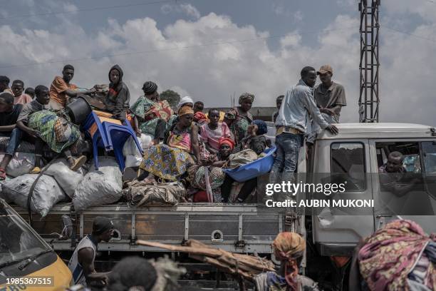 People ride a truck while carrying some of their belongings as they flee the Masisi territory following clashes between M23 rebels and government...