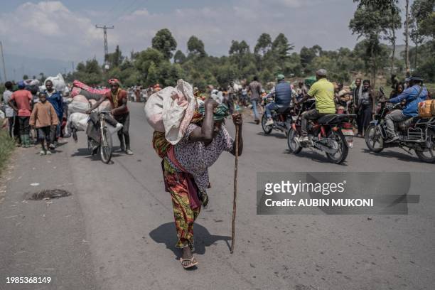 Woman carries some of their belongings as people flee the Masisi territory following clashes between M23 rebels and government forces, at a road near...