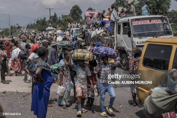 People carry some of their belongings as they flee the Masisi territory following clashes between M23 rebels and government forces, at a road near...
