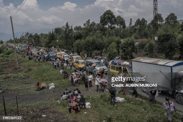 Vehicles and people crowd together at a busy road as they flee the Masisi territory following clashes between M23 rebels and government forces, at a...
