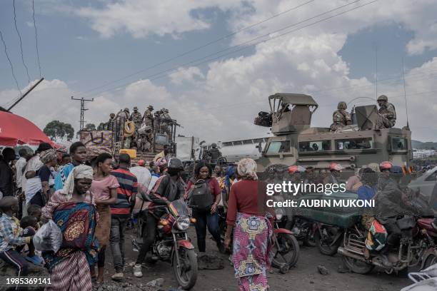 People gather next to some vehicles from the South African National Defence Force as part of the Southern African Development Community Mission as...