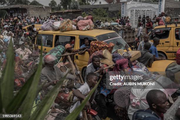 People gather at a busy road while carrying some of their belongings as they flee the Masisi territory following clashes between M23 rebels and...