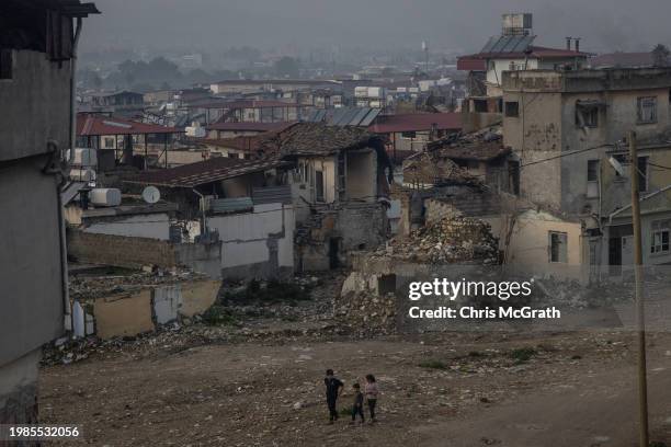 Children walk past houses destroyed by last years earthquake in Hatay's historical old town on February 04, 2024 in Hatay, Turkey. In the early hours...