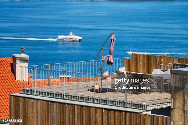 front view of a rooftop of a building in the city of vigo with table and umbrella with the sea in the background. - vigo stock pictures, royalty-free photos & images