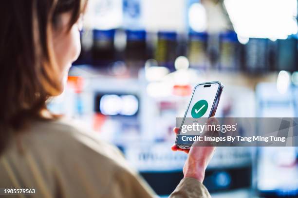 cheerful asian businesswoman confirming travel schedules using app on smart phone at airport - registro fotografías e imágenes de stock