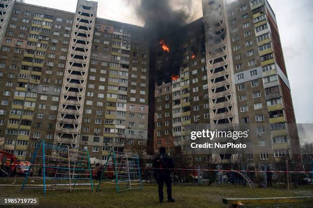 Local residents are watching as smoke rises from a burning residential high-rise building damaged by a massive Russian missile strike in Kyiv,...