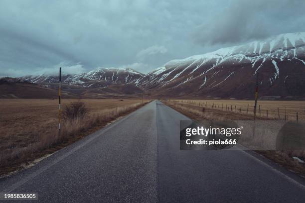 winter apennine landscapes of sibillini park: straight road - castelluccio stock pictures, royalty-free photos & images