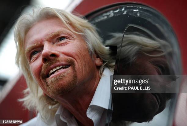 British entrepreneur Sir Richard Branson leans out of the window of the drivers cab on board a Virgin Pendolino train at Lime Street Station in...