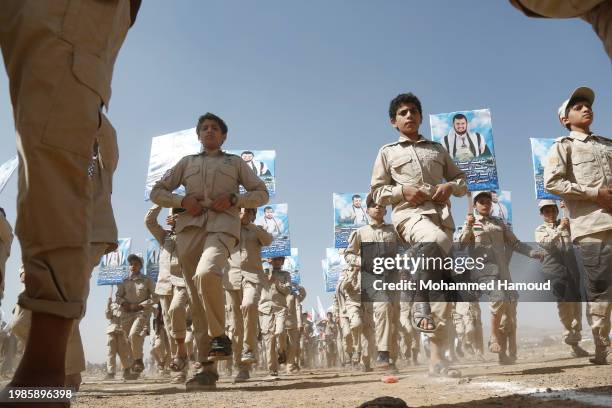 Scout team members carry Yemeni and Palestinian flags and placards depicting Yemen's Houthi leader Abdul Malek Bader AL-Den Al-Houthi and Houthi...