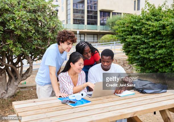 multiethnic group of young students sitting outdoors and studying together on their laptops - laptop netbook stock pictures, royalty-free photos & images