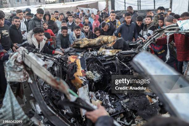 Palestinians inspect a destroyed car following the Israeli attacks in Rafah, Gaza on February 7, 2024.