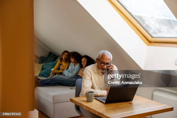 senior man working from home with family in background - skylight stock pictures, royalty-free photos & images