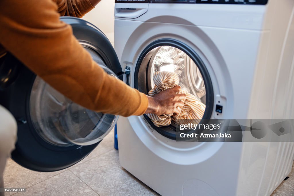 Person, die Wäsche in die Waschmaschine lädt