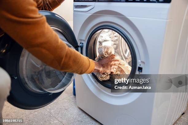 persona cargando ropa en la lavadora - lavadora fotografías e imágenes de stock