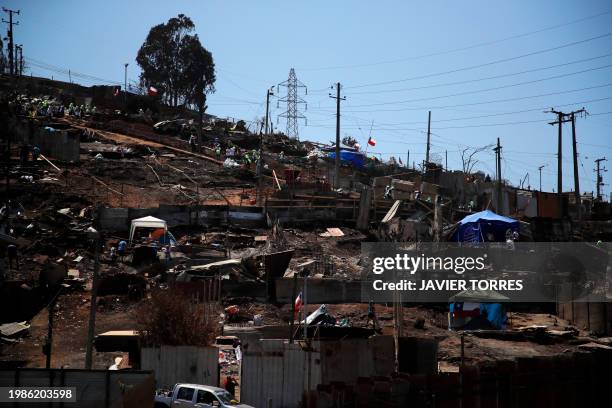 Residents remove debris from burned houses after a forest fire in the Poblacion Monte Sinai neighborhood in Viña Del Mar, Chile, on February 7, 2024....