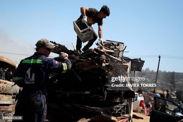 Residents remove debris from burned houses after a forest fire in the Poblacion Monte Sinai neighborhood in Viña Del Mar, Chile, on February 7, 2024....